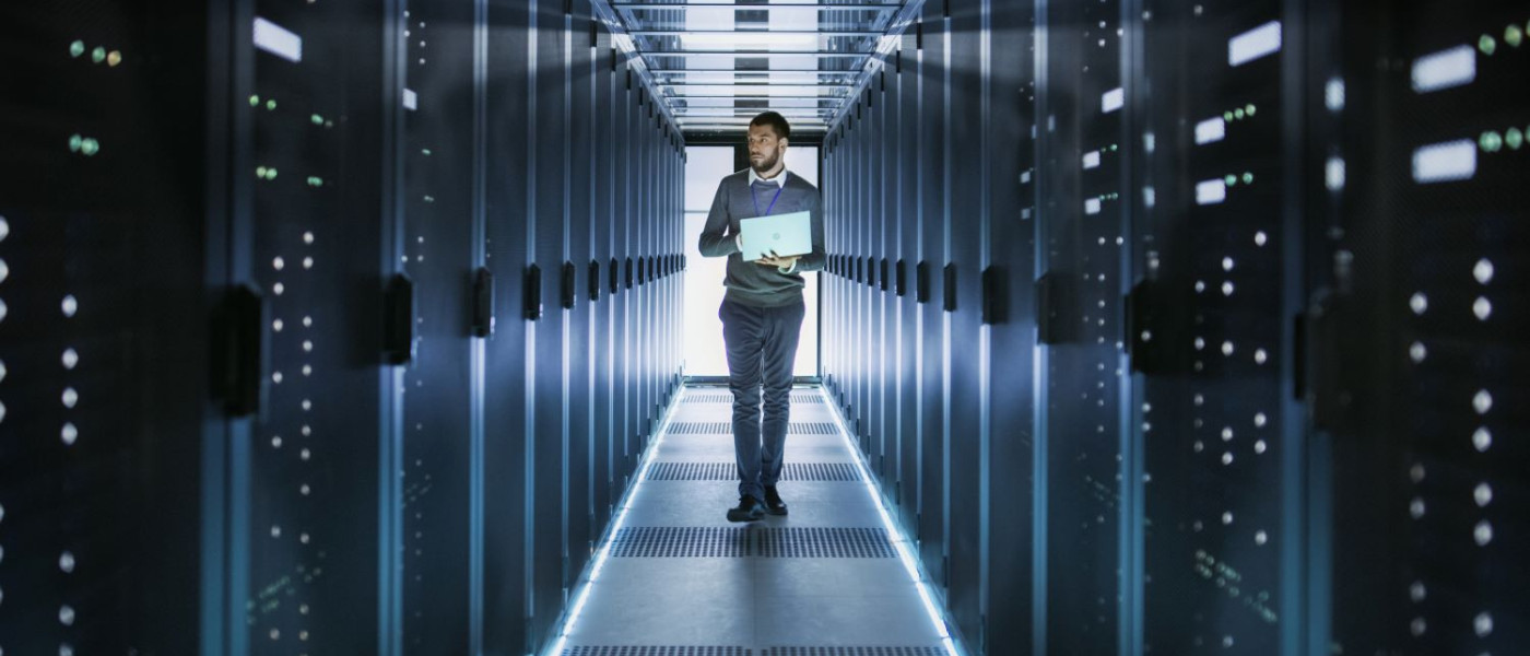 Un technicien dans un couloir d'ordinateurs dans un data centre