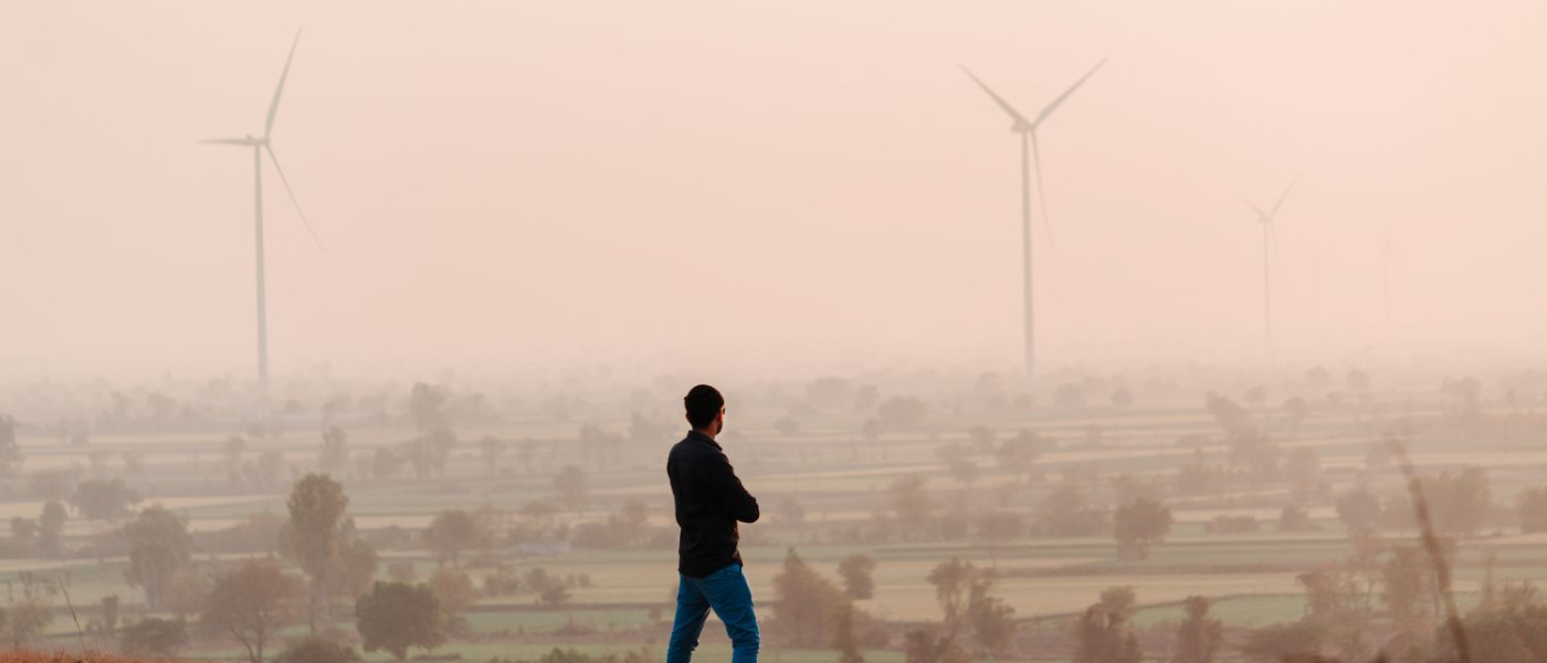 Un homme indien debout au sommet d'une colline devant les éoliennes pendant le coucher de soleil à Wankaner, Gujarat, Inde.
