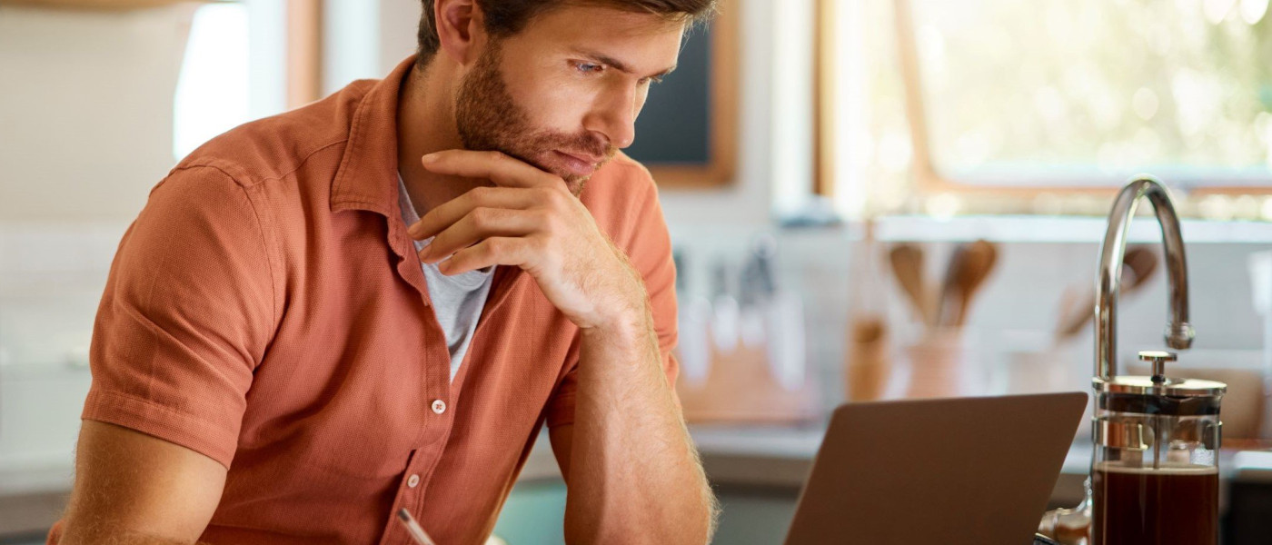 Jeune homme travaillant sur son ordinateur portable dans sa cuisine