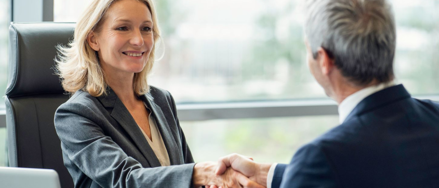 Femme d’affaires souriante au bureau serrant la main d’un homme d’affaires