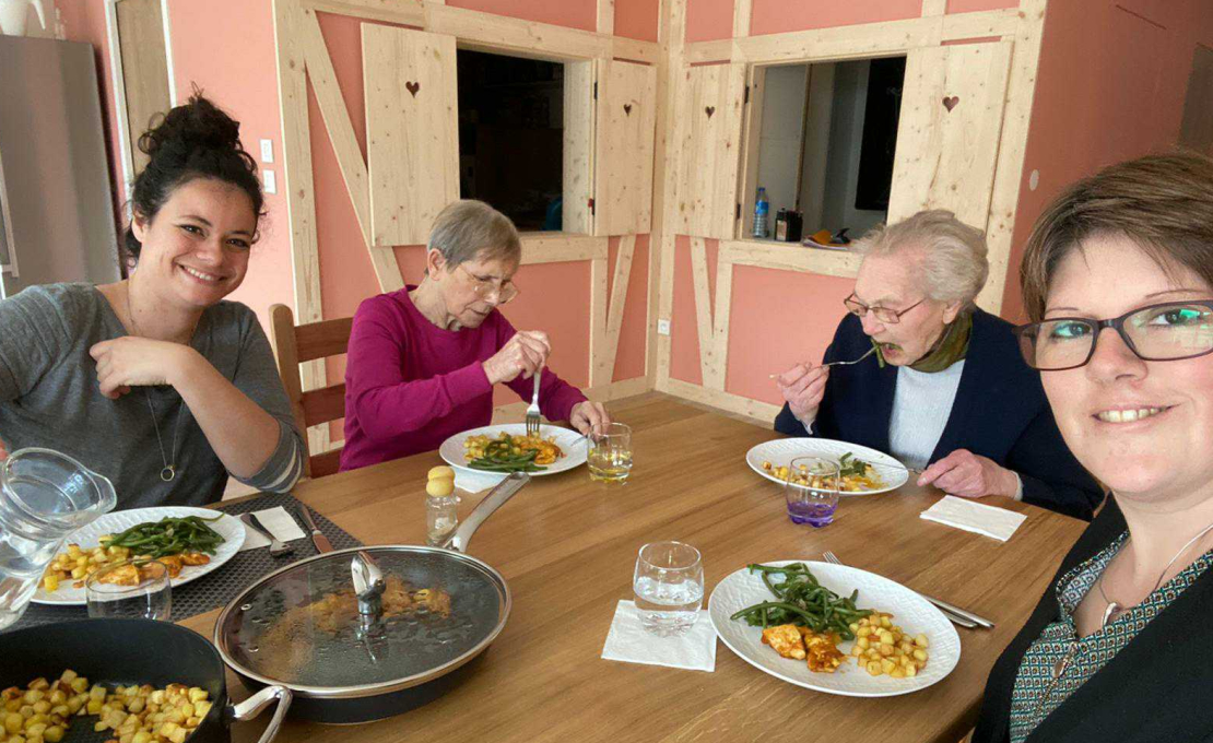 Photo de locataires d'un habitat inclusif de l'association Familles Solidaires, accompagnée par BNP Paribas Asset Management, en train de déjeuner avec deux aides à domicile