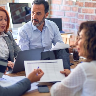 Groupe de travailleurs d’affaires travaillant ensemble. S’asseoir sur un bureau à l’aide d’un ordinateur portable pour lire des documents au bureau.