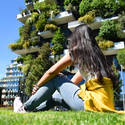 jeune femme assise devant immeuble moderne avec façade végétale