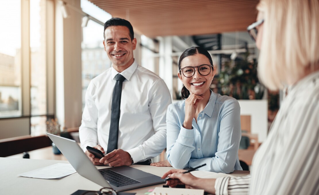 Groupe de personnes souriantes travaillant autour d'un bureau