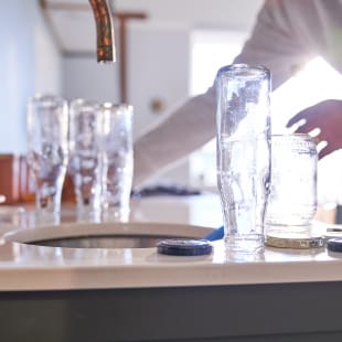 Homme qui lave des bouteilles en verre dans la cuisine