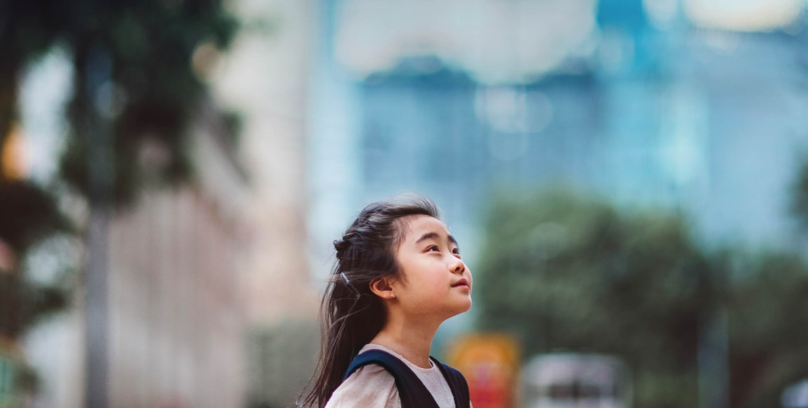 Petite fille regardant vers le ciel devant barre d'immeubles.