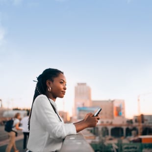Femme avec son téléphone portable dans la main regardant vers l'horizon