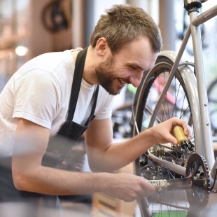 Homme qui répare dans un atelier à vélo qui applique de l'huile à la courroie