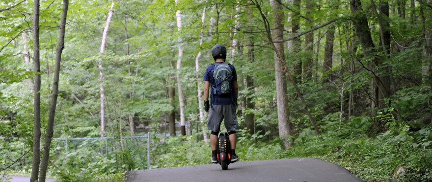 Un homme se balade sur un gyroroue dans un parc