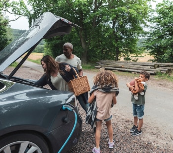 Famille autour d'une voiture éléctrique dans la campagne