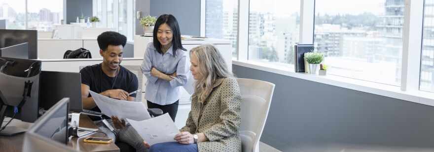 Cheerful colleagues reviewing paperwork in coworking space