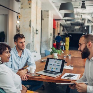 three people are talking around a desk office