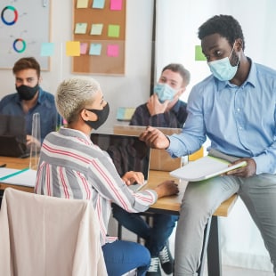 Jeunes gens travaillant au sein d'un bureau, avec masque sur le visage