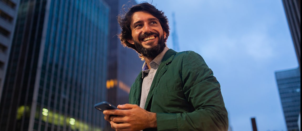 Un homme sourit en tenant son téléphone