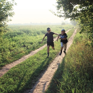 Deux enfants jouant à chat sur un chemin de campagne.