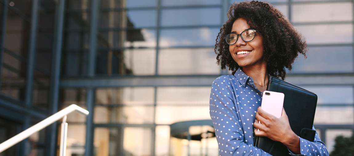 Jeune femme souriante devant un immeuble