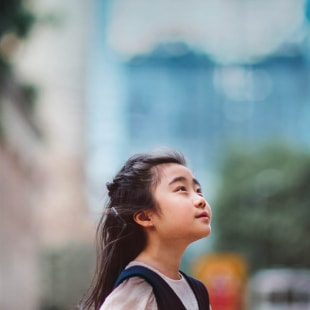 Petite fille regardant vers le ciel devant barre d'immeubles.