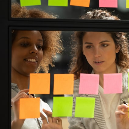 2 femmes devant une fenêtre rempli de post-its