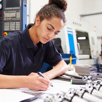 Engineer Planning Project With CNC Machinery In Background