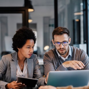 Two colleagues at the office, using a digital tablet