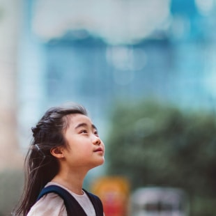 Petite fille regardant vers le ciel devant barre d'immeubles.