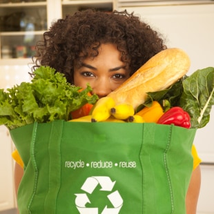 Jeune femme noir portant sac de produits alimentaires avec enseigne recyclable