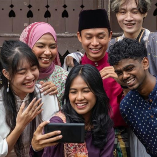 Groupe d'étudients malaisiens en costume traditionnelle prenant un  'selfie' avec un téléphone mobile