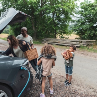 Family around and electric car in the country