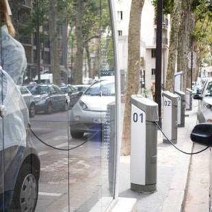 woman who rents an electric car in the city where a row of charging stations