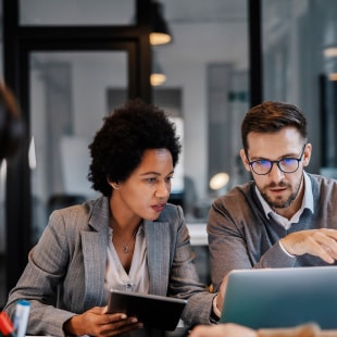 Two colleagues at the office, using a digital tablet