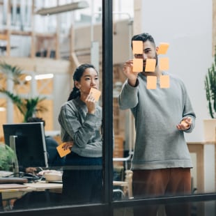 Deux personnes travaillant post-it vitre