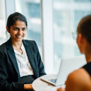 An Indian woman sitting by an accomplice inside a cafeteria.