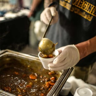 Homme versant de la soupe dans une cantine solidaire
