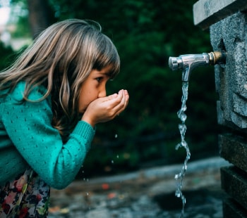 Girl drinking water from a fountain cupping her hands