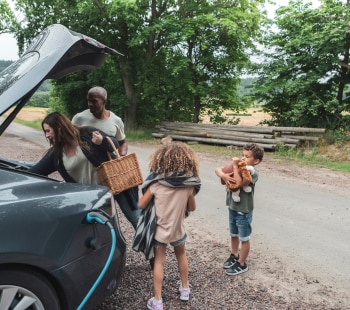 Family around and electric car in the country