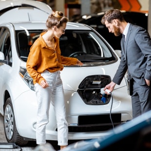 Sales manager with client near electric car at the car dealership
